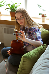 Image showing Young woman studying at home during online courses or free information by herself, playing violin, improvising