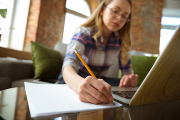 Image showing Young woman studying at home during online courses or free information by herself, making notes