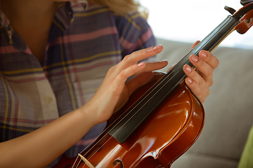 Image showing Young woman studying at home during online courses or free information by herself, close up shoot of violin