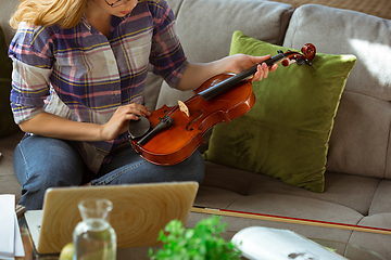 Image showing Young woman studying at home during online courses or free information by herself, playing violin, improvising