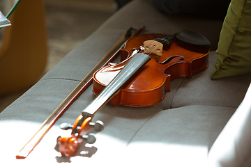 Image showing Close up shoot of violin lying on sofa in sunlight, hobby and music concept