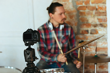 Image showing Caucasian musician playing drumms during online concert with the band at home isolated and quarantined, inspired improvising