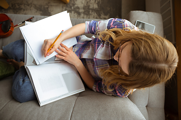 Image showing Young woman studying at home during online courses or free information by herself, making notes