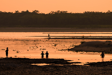 Image showing Asian women fishing in the river, silhouette at sunset