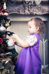 Image showing Little girl  is decorating christmas tree