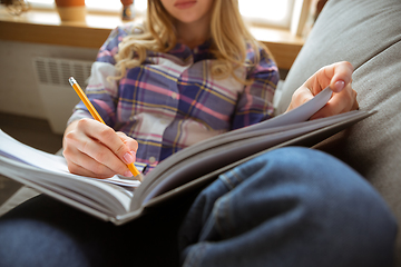 Image showing Young woman studying at home during online courses or free information by herself, making notes