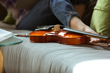 Image showing Young woman studying at home during online courses or free information by herself, close up shoot of violin