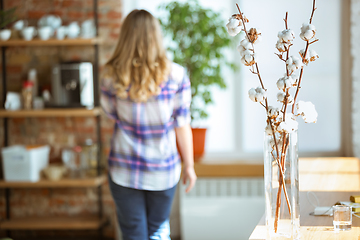 Image showing Portrait of gorgeous woman at home, cozy atmosphere, focus on flowers