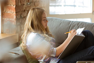 Image showing Young woman studying at home during online courses or free information by herself, making notes