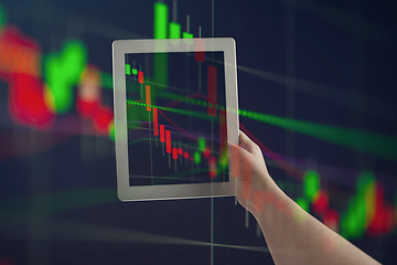 Image showing Hands holding tablet showing graphs going down. Double exposure with graphs, digital. Virus alert, coronavirus pandemic, crisis, unemployment