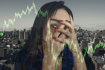 Image showing Stressed woman holding head with hands on abstract city background. Double exposure with graphs. Virus alert, coronavirus pandemic, crisis, unemployment