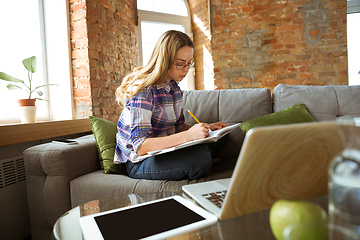 Image showing Young woman studying at home during online courses or free information by herself, making notes