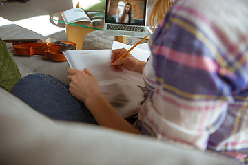 Image showing Young woman studying at home during online courses or free information by herself, making notes