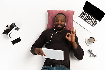 Image showing Emotional african-ameican man using gadgets isolated on white studio background, technologies connecting people. Online shopping, showing nice