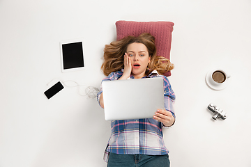 Image showing Emotional caucasian woman using gadgets isolated on white studio background, technologies connecting people. Crazy shocked