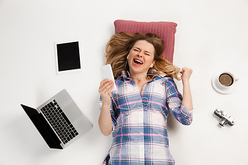 Image showing Emotional caucasian woman using gadgets isolated on white studio background, technologies connecting people. Betting, winner