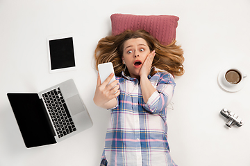 Image showing Emotional caucasian woman using gadgets isolated on white studio background, technologies connecting people. Crazy shocked