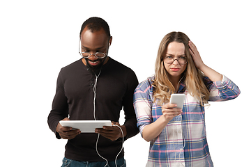 Image showing Emotional man and woman using gadgets on white studio background, technologies connecting people. Gaming, shopping, online meeting