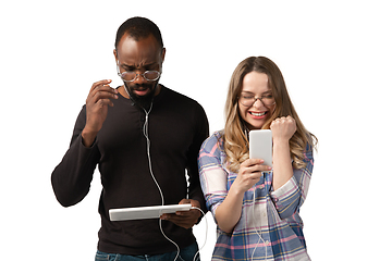 Image showing Emotional man and woman using gadgets on white studio background, technologies connecting people. Gaming, shopping, online meeting