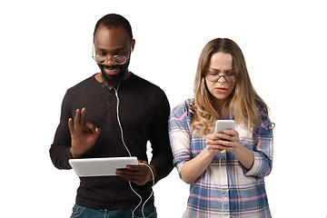 Image showing Emotional man and woman using gadgets on white studio background, technologies connecting people. Gaming, shopping, online meeting