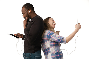 Image showing Emotional man and woman using gadgets on white studio background, technologies connecting people. Gaming, shopping, online meeting