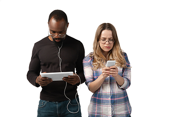 Image showing Emotional man and woman using gadgets on white studio background, technologies connecting people. Gaming, shopping, online meeting