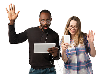 Image showing Emotional man and woman using gadgets on white studio background, technologies connecting people. Gaming, shopping, online meeting