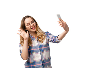 Image showing Emotional caucasian woman using smartphone isolated on white studio background, technologies. Taking selfie