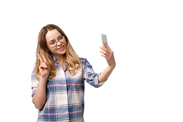 Image showing Emotional caucasian woman using smartphone isolated on white studio background, technologies. Taking selfie