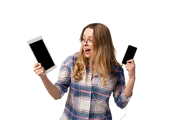 Image showing Emotional caucasian woman using gadgets on white studio background, technologies. Crazy happy shows tablet and smartphone