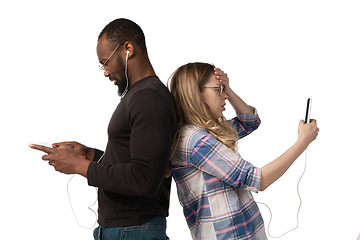 Image showing Emotional man and woman using gadgets on white studio background, technologies connecting people. Gaming, shopping, online meeting