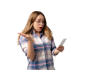 Image showing Emotional caucasian woman using smartphone isolated on white studio background, technologies. Listen to music, shocked