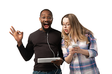 Image showing Emotional man and woman using gadgets on white studio background, technologies connecting people. Gaming, shopping, online meeting