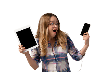 Image showing Emotional caucasian woman using gadgets on white studio background, technologies. Crazy happy shows tablet and smartphone