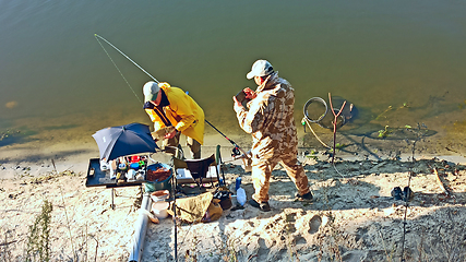 Image showing Men take pictures of caught bream. Fishing on river. Male hobby. Recreation