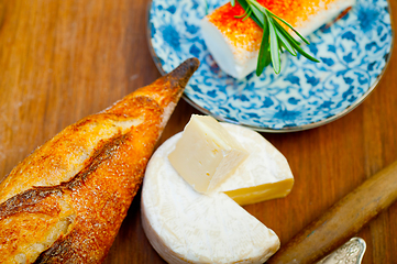 Image showing French cheese and fresh  baguette on a wood cutter