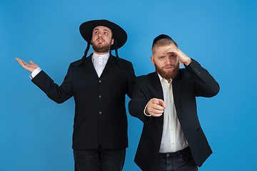 Image showing Portrait of a young orthodox jewish men isolated on blue studio background, meeting the Passover, astonished