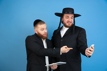 Image showing Portrait of a young orthodox jewish men isolated on blue studio background, meeting the Passover, astonished