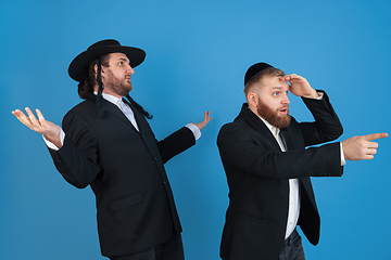 Image showing Portrait of a young orthodox jewish men isolated on blue studio background, meeting the Passover, astonished