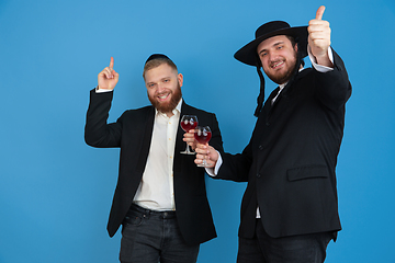 Image showing Portrait of a young orthodox jewish men isolated on blue studio background, meeting the Passover