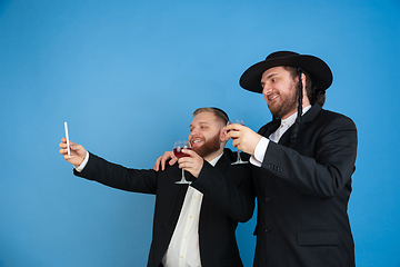 Image showing Portrait of a young orthodox jewish men isolated on blue studio background, meeting the Passover