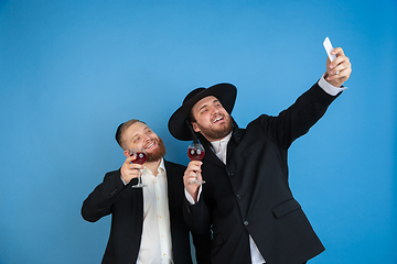 Image showing Portrait of a young orthodox jewish men isolated on blue studio background, meeting the Passover