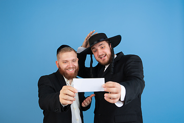 Image showing Portrait of a young orthodox jewish men isolated on blue studio background, meeting the Passover, winners