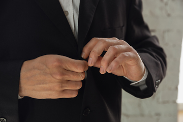 Image showing Close up of caucasian male hands, wearing classic black jacket