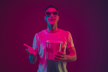 Image showing Caucasian man\'s portrait isolated on pink-purple studio background in neon light, wearing 3D-cinema eyewear