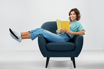 Image showing happy young woman in armchair reading book