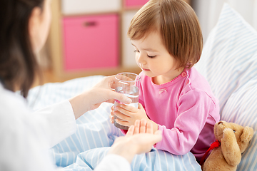 Image showing doctor giving medicine to sick girl in bed at home