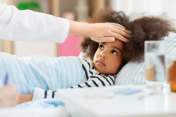 Image showing doctor with clipboard and sick girl in bed at home