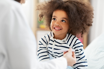 Image showing doctor showing thermometer to smiling sick girl