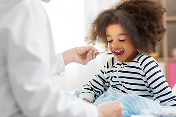 Image showing doctor giving medicine to sick girl in bed at home